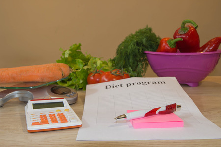vegetables, calculator and centimeter on a wooden table. Diet conceptの写真素材