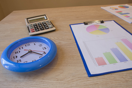Clock, calculator, pen, graphics on table. Business graph pictures. financial conceptの写真素材