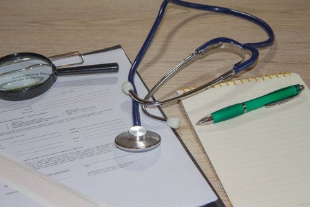 Stethoscope closeup with a clipboard on the desk. writing prescription on paper. Health and medical concept.の写真素材