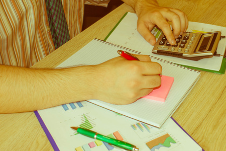 Businessman hand using calculator, accounting concept. Man hands with pencil, notebook and Calculator on wooden tableの写真素材