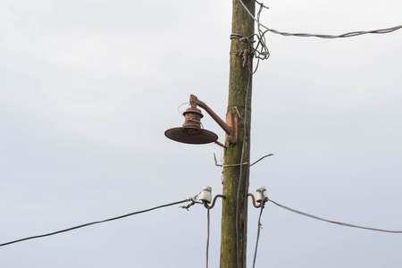 Old lantern on the electric pillar, cables. Power pole with wires against sky