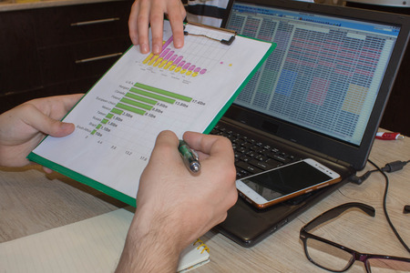 Businessman working on office desk with Calculator, a computer, a pen and document. Man, counting...