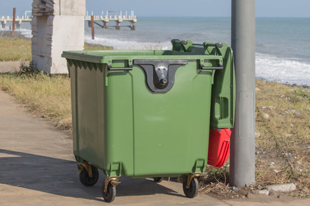 green trash box near the sea beach. Littering the beach and the seaの写真素材