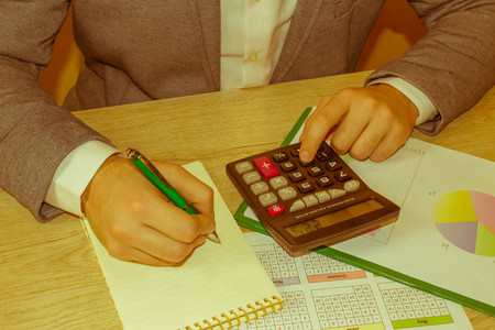 Close up of male hands on her calculator's keyboard. The second hand in on the touchpad. Concept of...