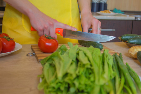 Young woman cooking healthy meal in the kitchen. Cooking healthy food at home. Woman in kitchen preparing vegetablesの写真素材