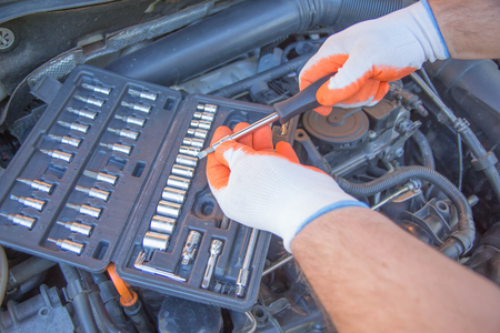 Worker repairs a car in a car repair center. Repair service. Maintenance of automotive. The mechanic is repairing the carの写真素材