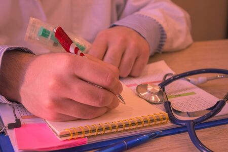 Doctor working at table in office. doctor concept in hospital. Hands of a doctor filling prescription, documents at the deskの写真素材