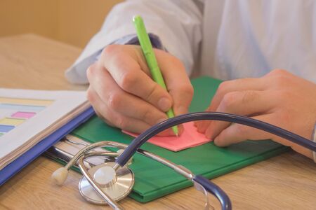 Doctor working at table in office. doctor concept in hospital. Hands of a doctor filling prescription, documents at the deskの写真素材