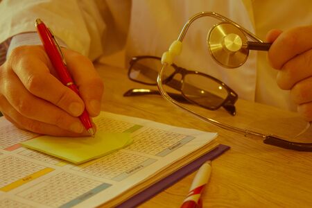 Physician working with paper in hospital office room. Therapeutist sitting at working table making...