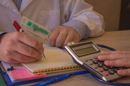 Healthcare costs and fees concept. Hand of smart doctor and female used a calculator for medical costs in modern hospitalの写真素材