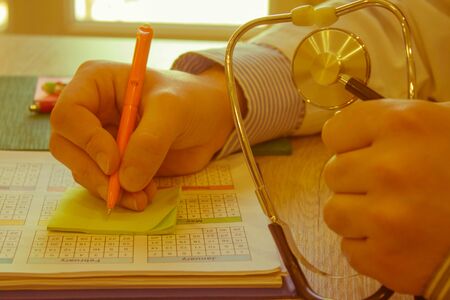 Doctor sits in a medical office in the clinic and writes medical history. Healthcare and medical...