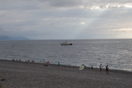 Distant Navy ship on vast blue Pacific sea. Sunset sea ship silhouette view. Black sea Coast guard boat on sunsetの写真素材