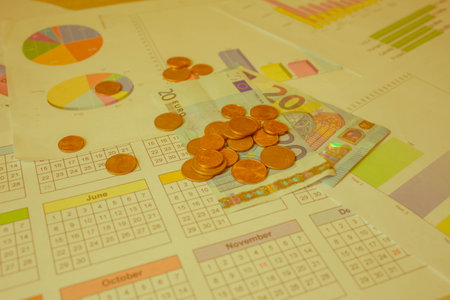 stacked euro coins on table sheet with chart of exchange market. Business, finance, saving money or investment conceptの写真素材
