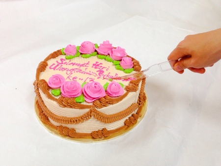 Woman hand cutting happy anniversary cake