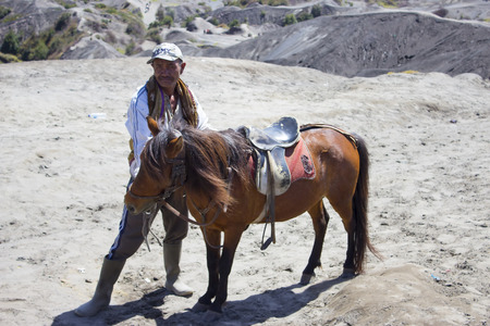 JAVA,INDONESIA-APR 9:Indonesia man with the horse for tourist rent at Mount Bromo on April 9, 2014 in Java, Indonesia.Mt. Bromo is an active volcano and part of the Tengger massif, in East Java.のeditorial素材