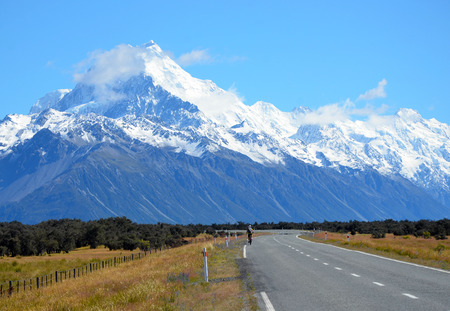 Adventurous person riding a bike on the road to the mountainsの写真素材