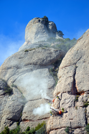 Workmen abseiling, suspended from and drilling the sides of the mountains of Montserrat, Catalonia, Spainの写真素材