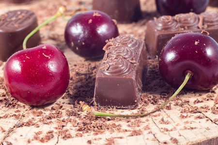 Dark chocolate with cherry on wooden table. Chocolate crumbの写真素材