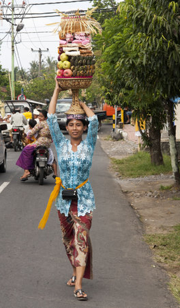 BALI, INDONESIA - JUL 8TH  A woman carries a basket of fruit to the temple on July 8th 2011 during the Galungan festival which is held in the 11th week of the 210-day Pawukon calendar のeditorial素材
