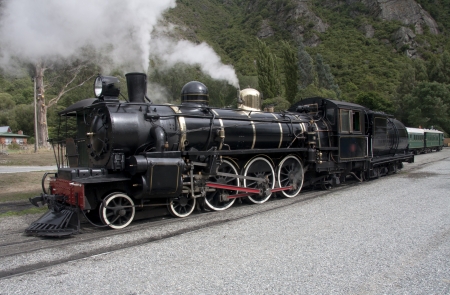 Steam locomotive slowly moving along train tracksの写真素材