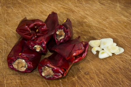 Dried red chillies and chopped garlic on a brown chopping boardの写真素材