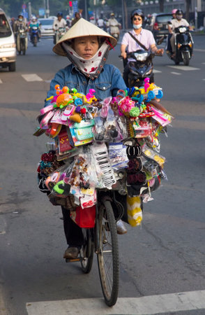 Ho Chi Minh City, Vietnam-October 29th 2013  A trinket vendor riding her bicycle through the Ho Chi Minh traffic  Bicycles have been replaced by motorcycles as the main form of transport in Vietnam のeditorial素材