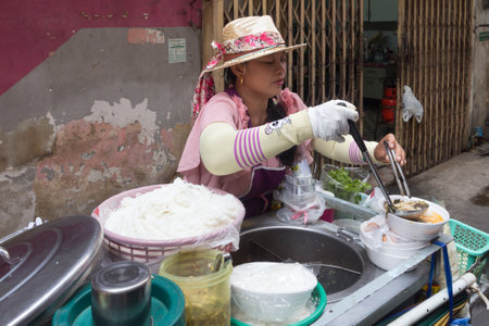 Bangkok, Thailand - March 19th 2015: Woman street food vendor ladling soup and noodles for a customer, The city is famous for its street food.のeditorial素材