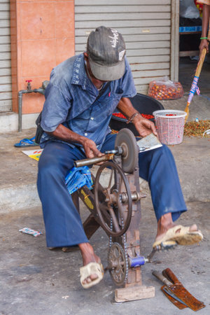 Mae Sot, Thailand - November 20th 2011: Man sharpening tools on a grinding wheel. The town is close to the Burmese border.のeditorial素材