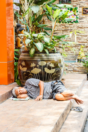 Bangkok, Thailand - 4th August 2017: Old man asleep on some steps. Vagrancy is an ever increasing...