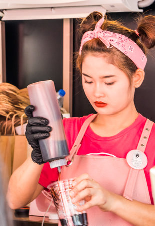 Bangkok, Thailand - January 30th 2019:A young Thai girl making a chocolate ice cream drink. Thais enjoy sweet drinks and ice cream.のeditorial素材