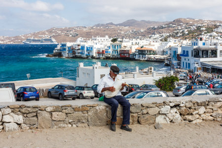 Mykonos, Greece - September 15th 2015: Old man sat on wall with bagpipe. The island is a popular tourist destination.のeditorial素材