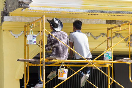 Bangkok, Thailand - November 12th 2015 : Men sat on scaffolding painting a house. Many properties are being renovated.のeditorial素材