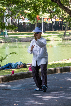 Bangkok, Thailand - 27th September 2018: Woman practising Tai Chi in Lumphini Park lake. The park is in the centre of the city.のeditorial素材