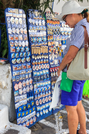 Mykonos, Greece - September 15th 2015: Woman tourist looking at souvenir fridge magnets in Chora. This is the main town on the island.のeditorial素材