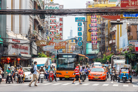 Bangkok, Thailand - March 23rd 2015: People crossing in front of traffic in Chinatown. Traffic is notoriously bad in the city.のeditorial素材