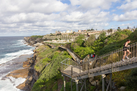 Sydney, Australia - June 20th 2015: A female jogger runs up steps on the Eastern beaches coastal pathway. Waverley cemetery is in the background.のeditorial素材