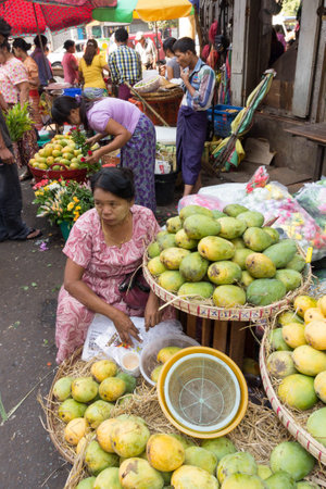 Yangon, Myanmar - May 6th 2014: A woman selling fruit on a street markets. Markets are found all over the city.のeditorial素材