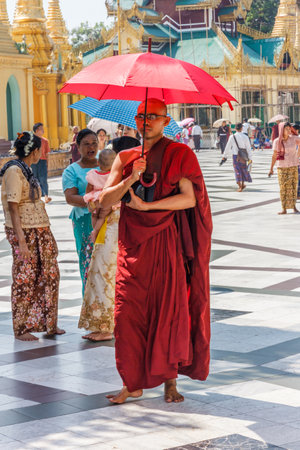 Yangon, Myanmar - May 6th 2014: Monk with umbrella in Shwedagon Pagoda. The pagoda is the most sacred in all of Myanmar.のeditorial素材
