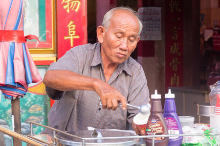 Chiang Mai, Thailand - November 22nd 2015: Man selling and serving ice cream outiside a Chinese temple. Coconut ice cream is a particular favourite,のeditorial素材