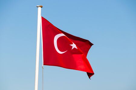Turkish flag fluttering in the breeze against a bright blue sky, Bodrum, Turkey