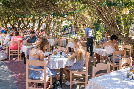 Kos, Greece - September 18th 2019: Restaurants shaded under bougainvillaea. The island is a popular tourist destinationのeditorial素材