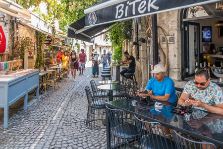 Alacati, Turkey - September 4th 2019: Typical narrow cobbled street with cafes and restaurants. The town is popular with tourists in summerのeditorial素材