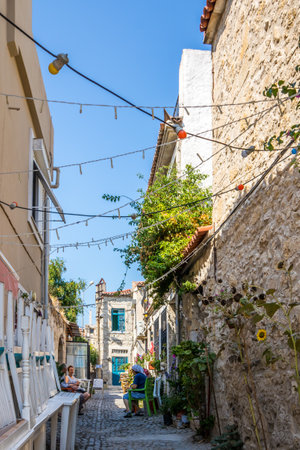 Alacati, Turkey - September 4th 2019: People sitting, talking in a narrow street, The town is a popular tourist destination.のeditorial素材