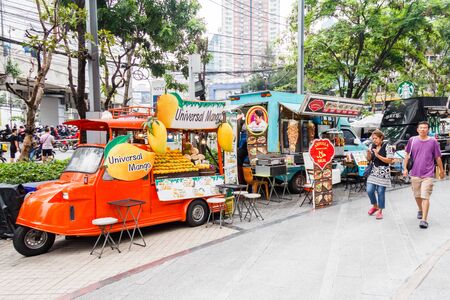 Bangkok, Thailand - 27th March 2018: People walking past  food trucks. Many different kinds of food are sold from the trucks.の写真素材