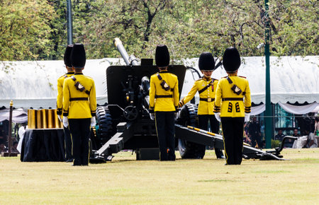 Bangkok, Thailand April 9th 2012: Thai soldiers in yellow uniforms firing gun salute outside the...