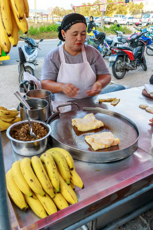 Phuket, Thailand - January 7th 2016: A woman making banana pancakes on a market stall. This is a favourite dish of tourists and Thais alike.のeditorial素材