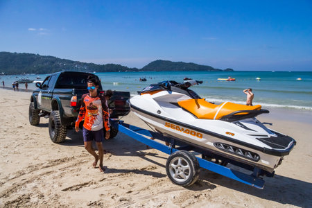Phuket, Thailand - 11th December 2017: Jetski operators attach a jetski to a truck on Patong Beach. Renting of jetskis is a controversial activity.のeditorial素材