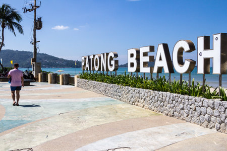 Phuket, Thailand - 11th December 2017: A man walks past a Patong beach sign. Oatong is Phuket's most popular beach.のeditorial素材