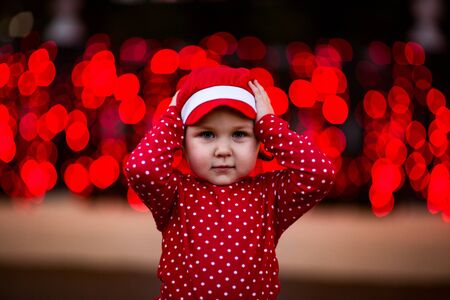 A little, cool girl in red clothes and a cap.