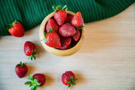 strawberry berries, red and ripe, on a light wooden background, in a wooden Cup